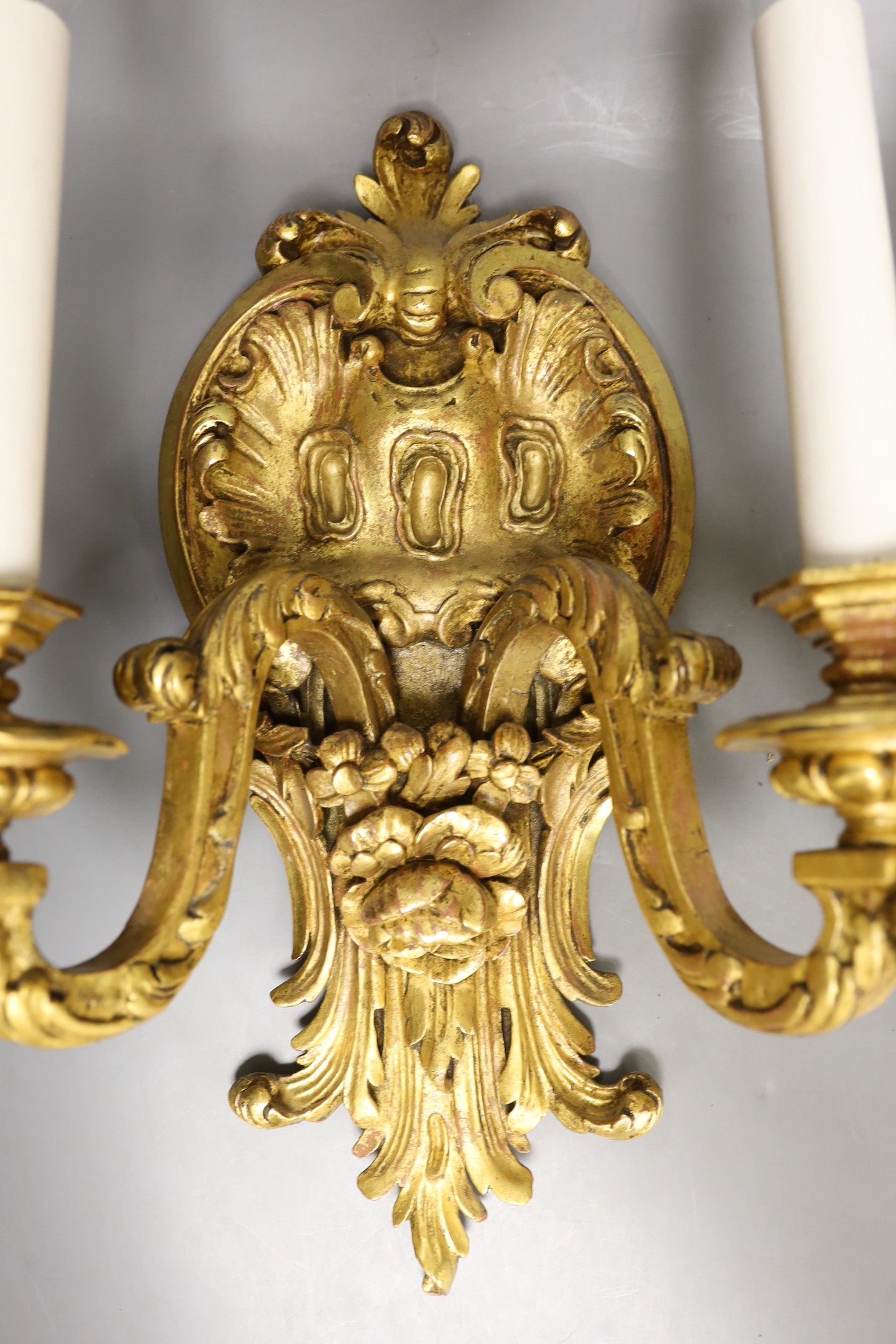 A pair of gilt carved wooden two branch wall sconces, 42 cms high.